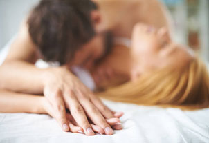 Imagen de un hombre y una mujer en la cama el hombre aguantando la mano de la mujer